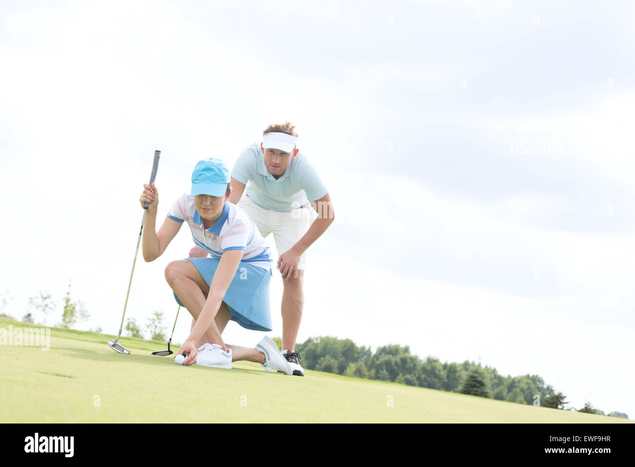 Metà di uomo adulto guardando donna sfera di puntamento sul campo da golf Foto Stock