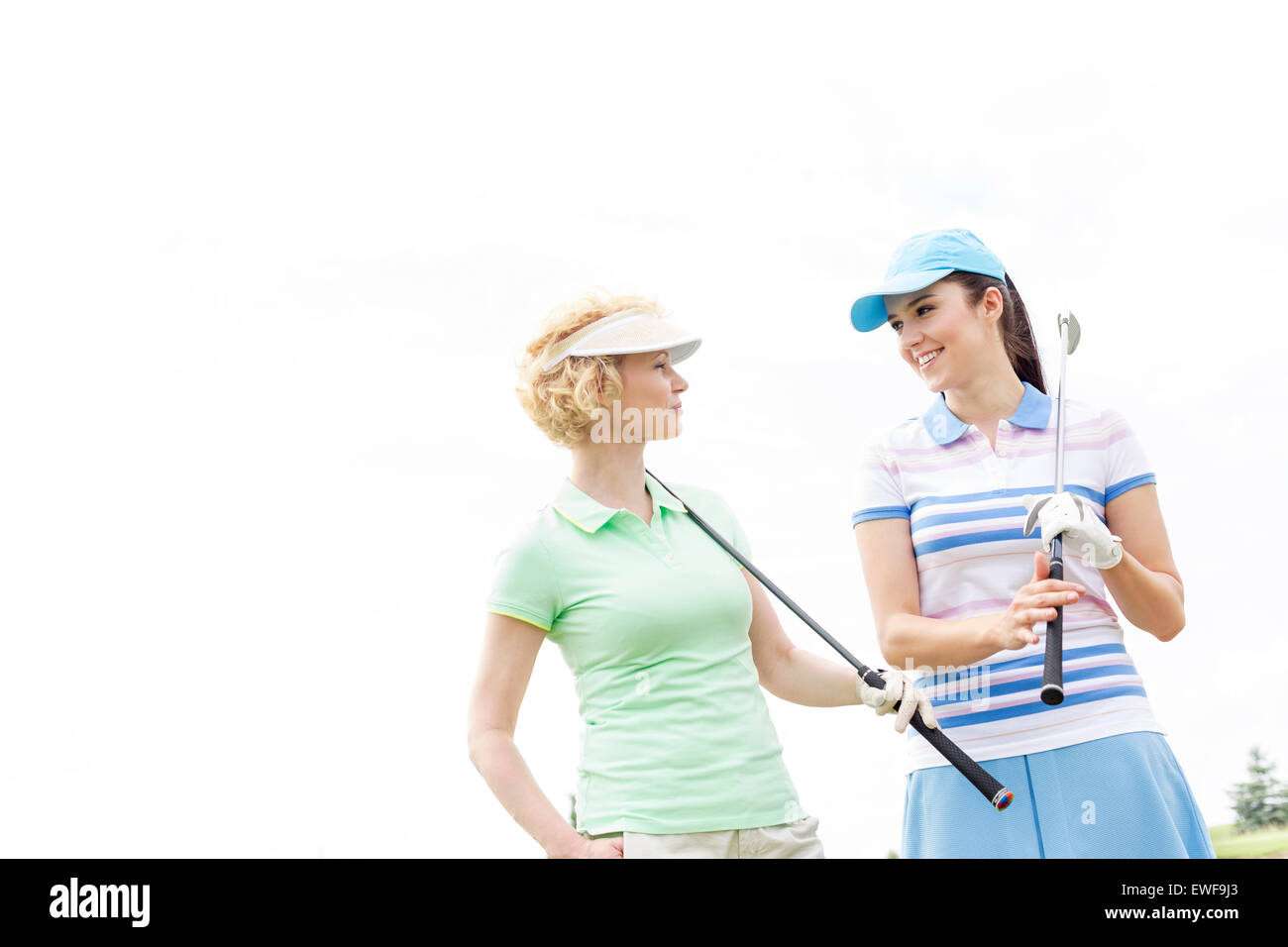 Felice golfisti femmina guardando ogni altro contro il cielo chiaro Foto Stock