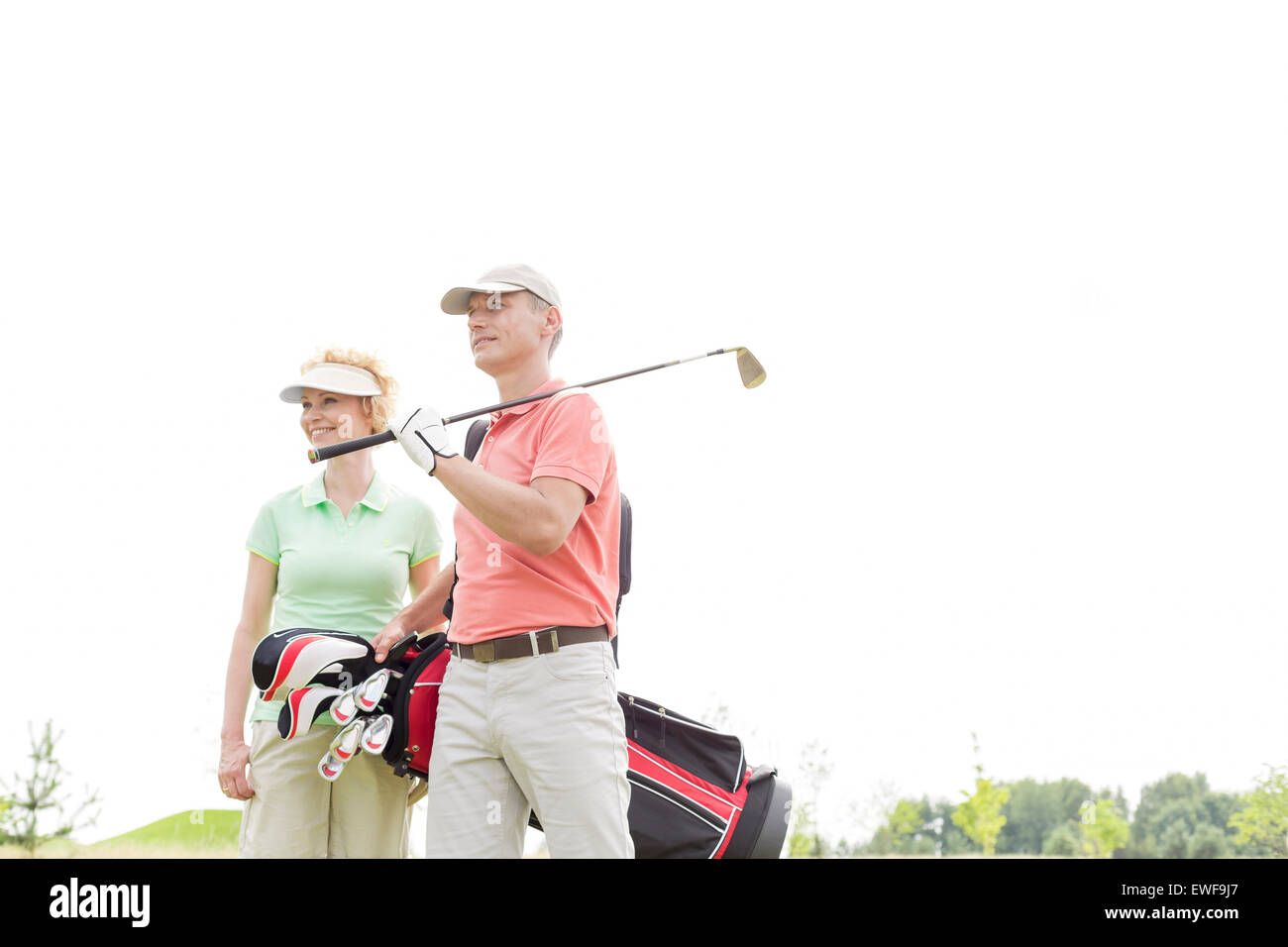 Basso angolo di vista di sorridere i golfisti in piedi contro il cielo chiaro Foto Stock