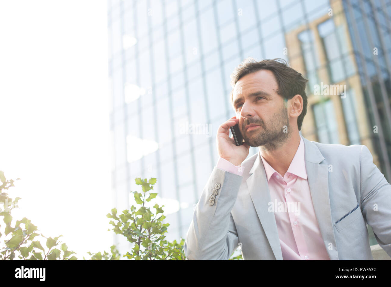 Imprenditore risposta cellulare al di fuori di edificio per uffici Foto Stock