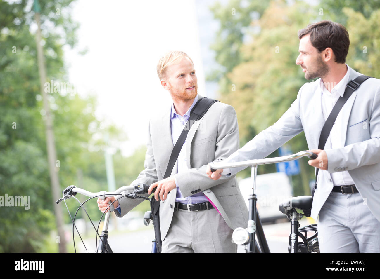 Imprenditori guardando ogni altra mantenendo le biciclette all'aperto Foto Stock