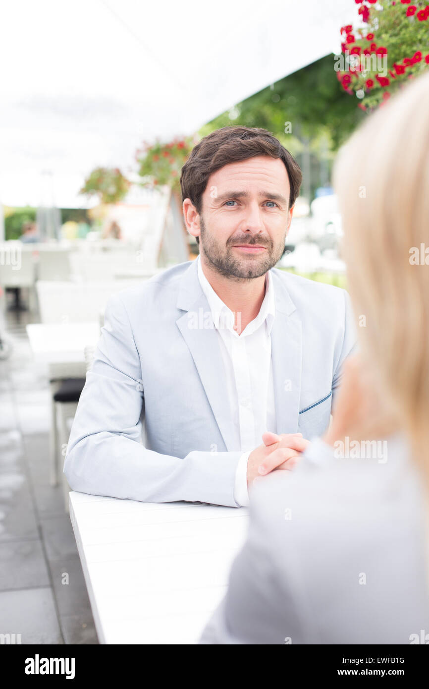 Imprenditore pensieroso seduto con il collega di sesso femminile al cafè sul marciapiede Foto Stock