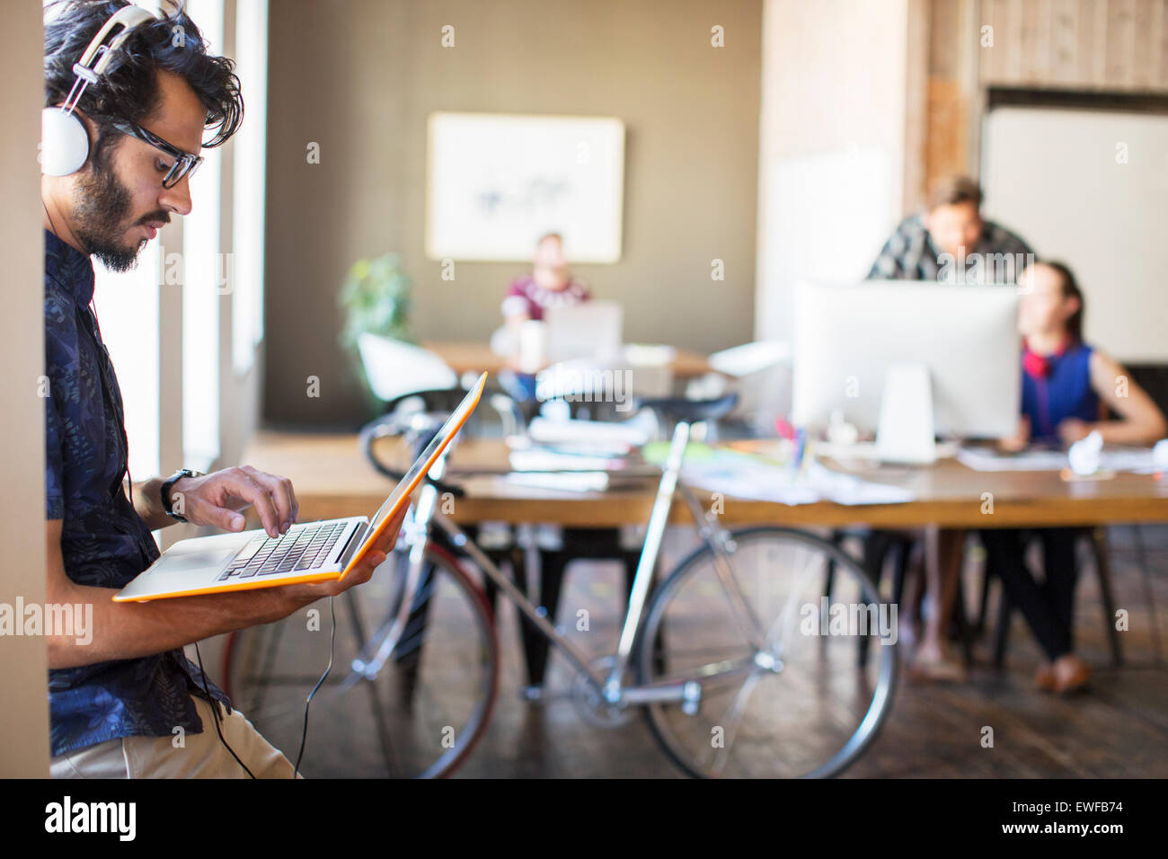 Casual uomo d affari con le cuffie utilizzando computer portatile in ufficio Foto Stock