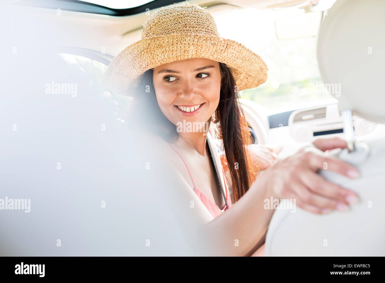 Donna felice guardando indietro mentre si guida auto Foto Stock