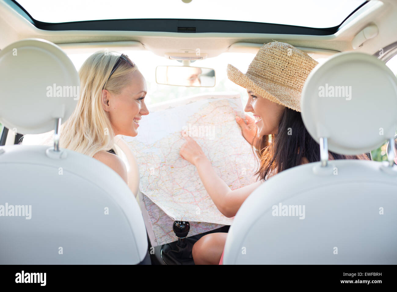Vista posteriore di felici donne lettura mappa in auto Foto Stock