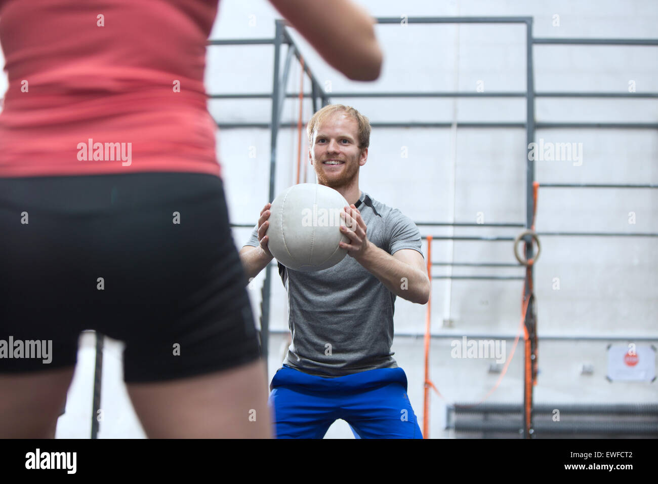 Felice l'uomo medicina lanciando la palla verso la donna in palestra crossfit Foto Stock