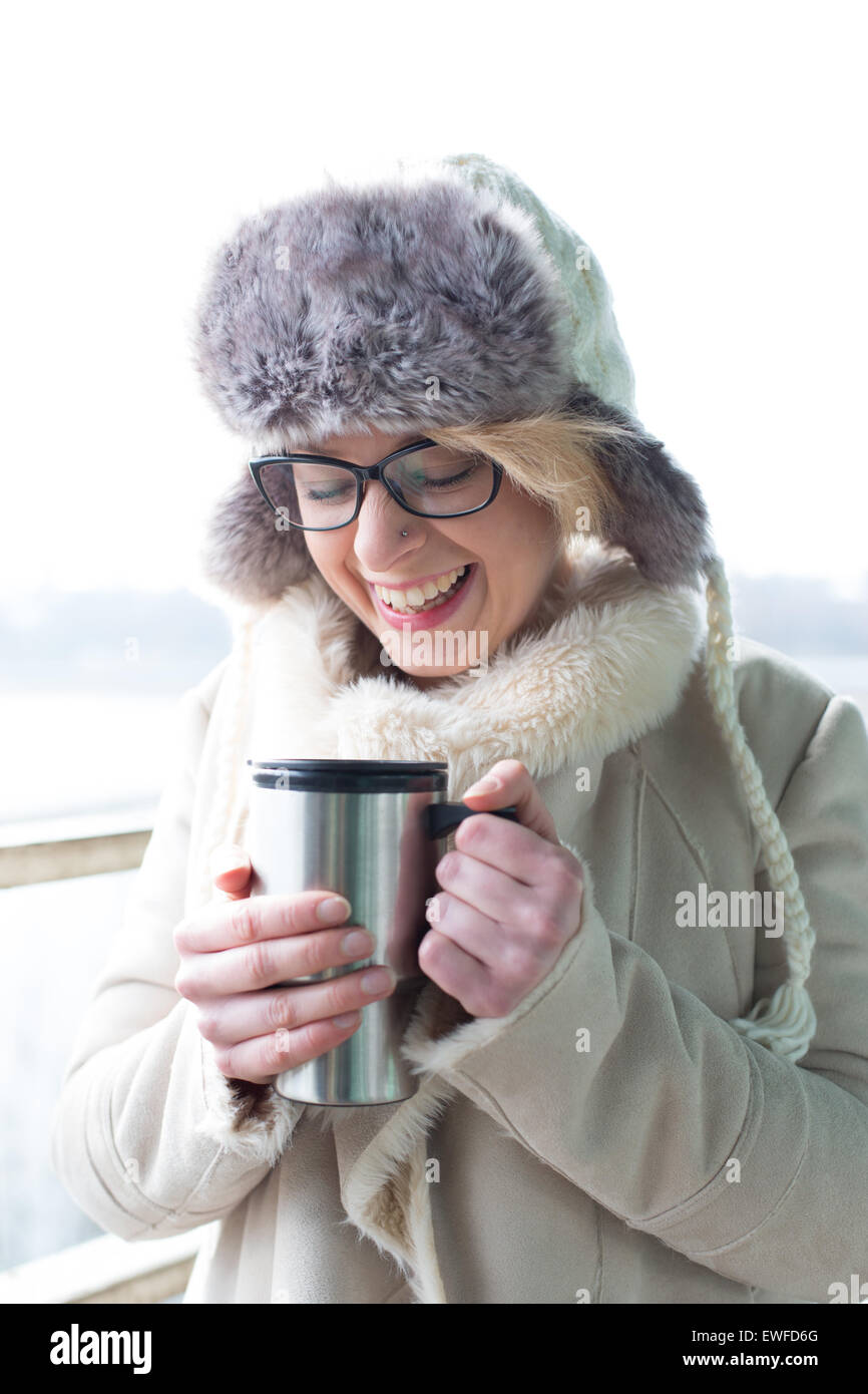 Allegra donna in abiti caldi tenendo isolato di contenitore per bevande Foto Stock
