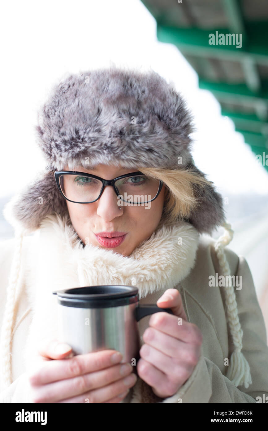 Ritratto di donna caffè di soffiaggio in isolato di contenitore di bevande durante il periodo invernale Foto Stock