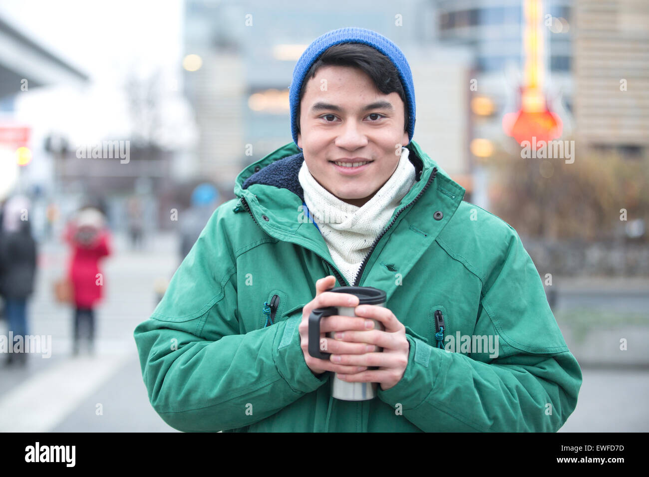 Ritratto di uomo in abbigliamento invernale sorridente su una strada di città Foto Stock