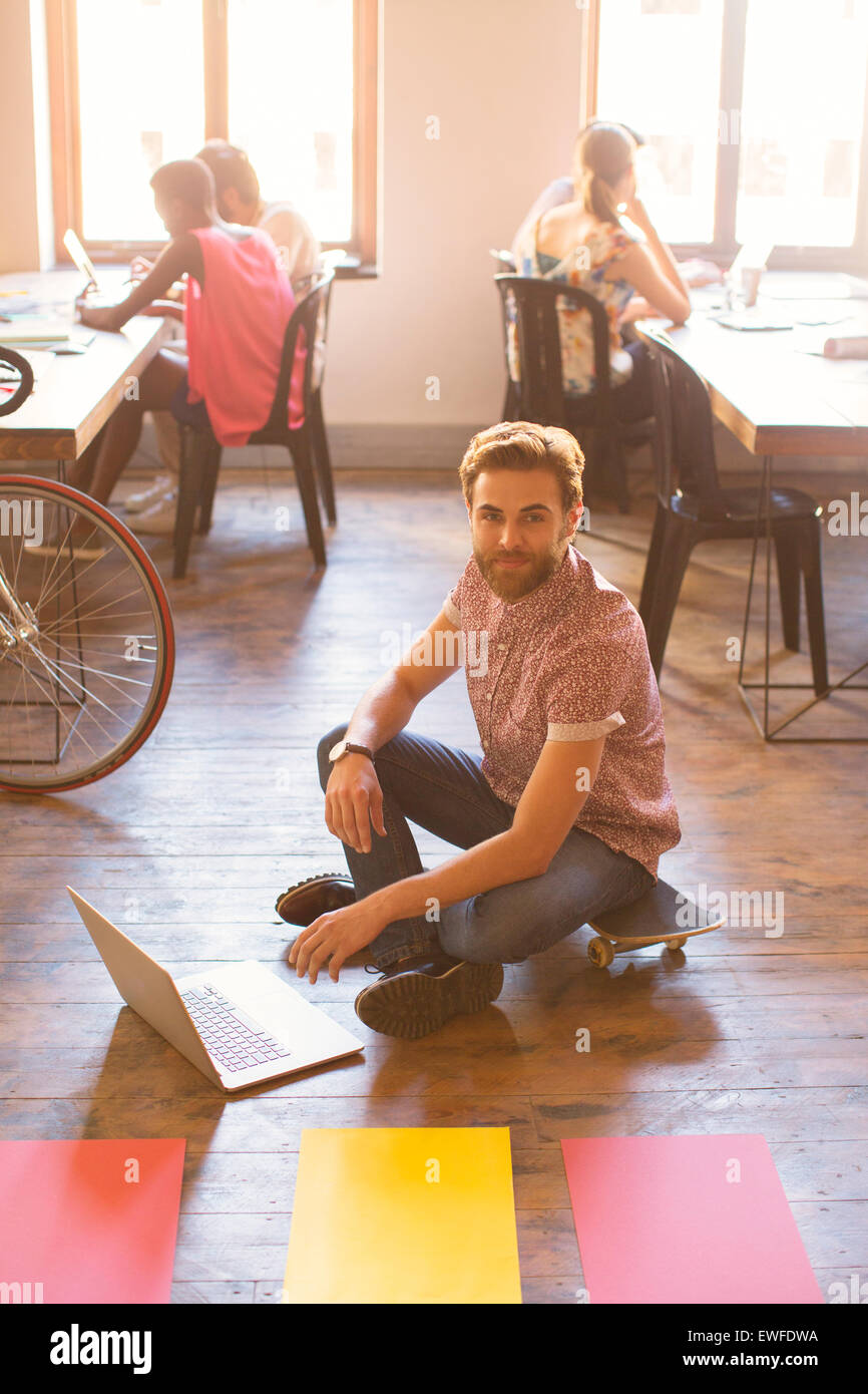 Ritratto di imprenditore creativo lavorando sul computer portatile sul pavimento Foto Stock