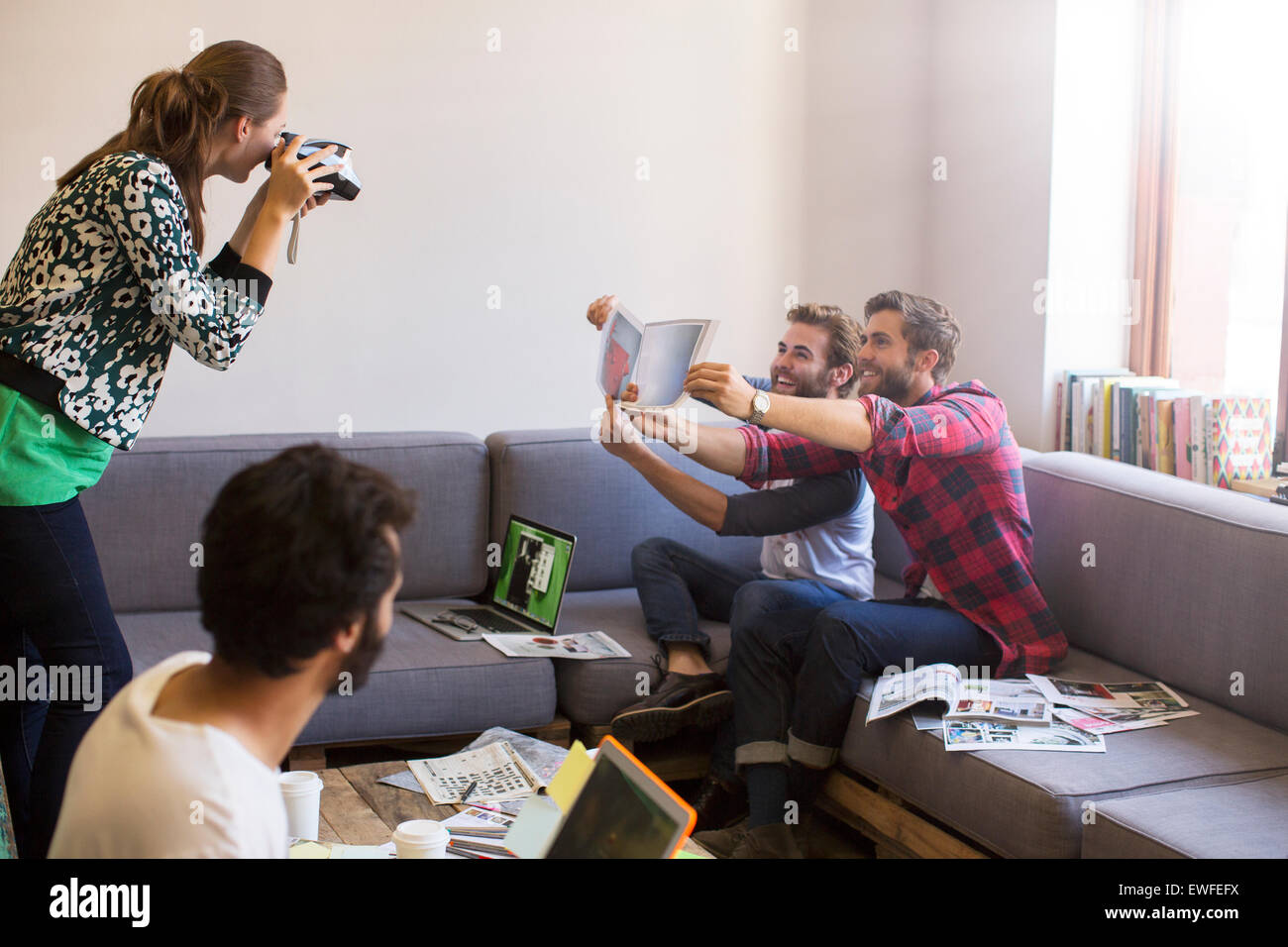 Gli imprenditori creativi con prove di posa per collaboratore con fotocamera istantanea Foto Stock