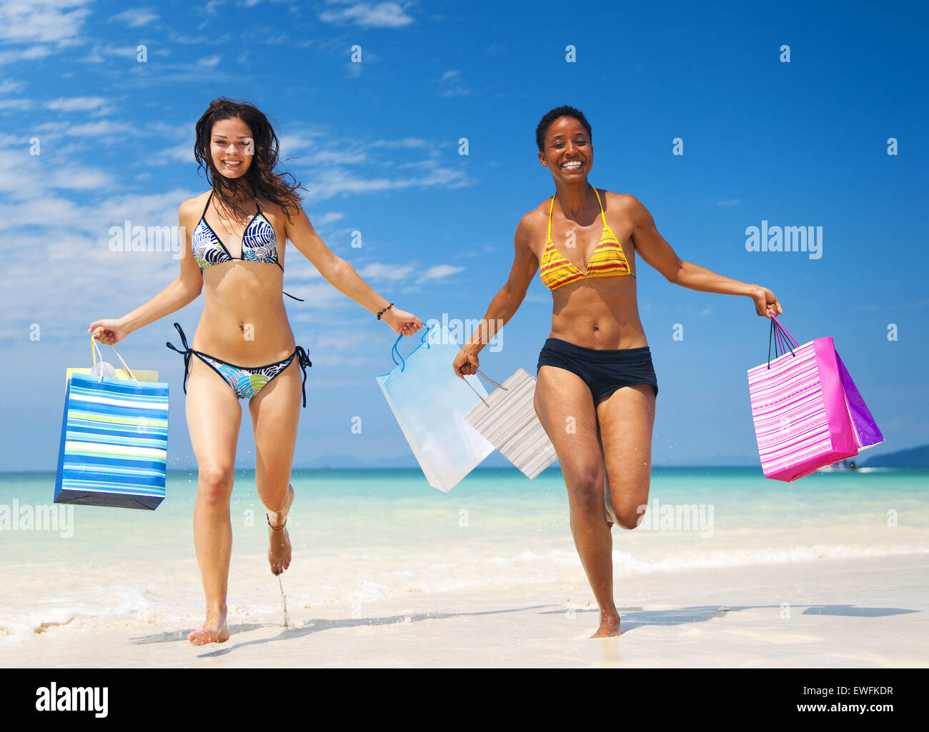 Le donne con le borse della spesa su una spiaggia tropicale. Foto Stock