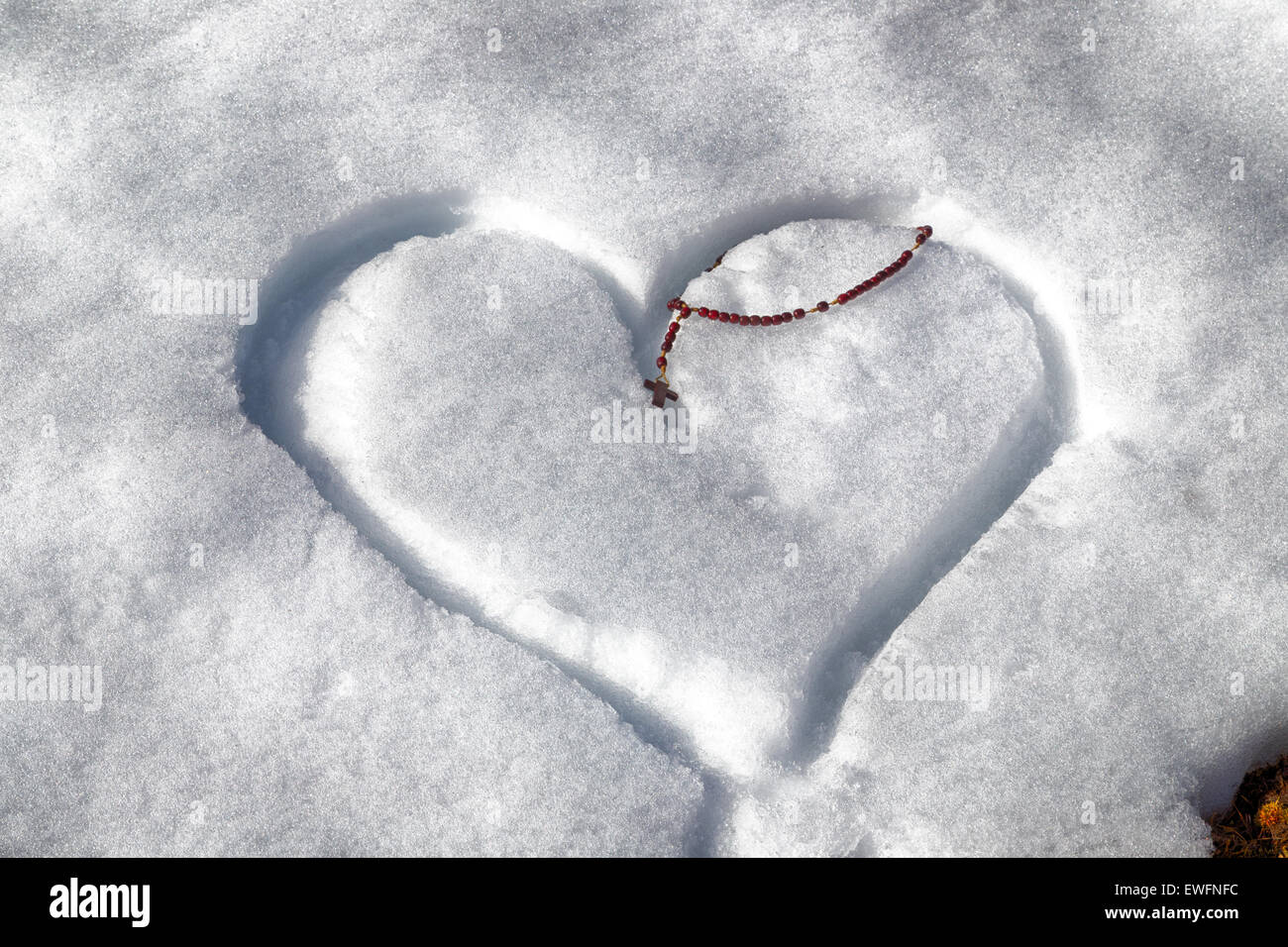 Rosario in legno Talloni a sinistra su un cuore disegnato a mano nella neve fresca Foto Stock