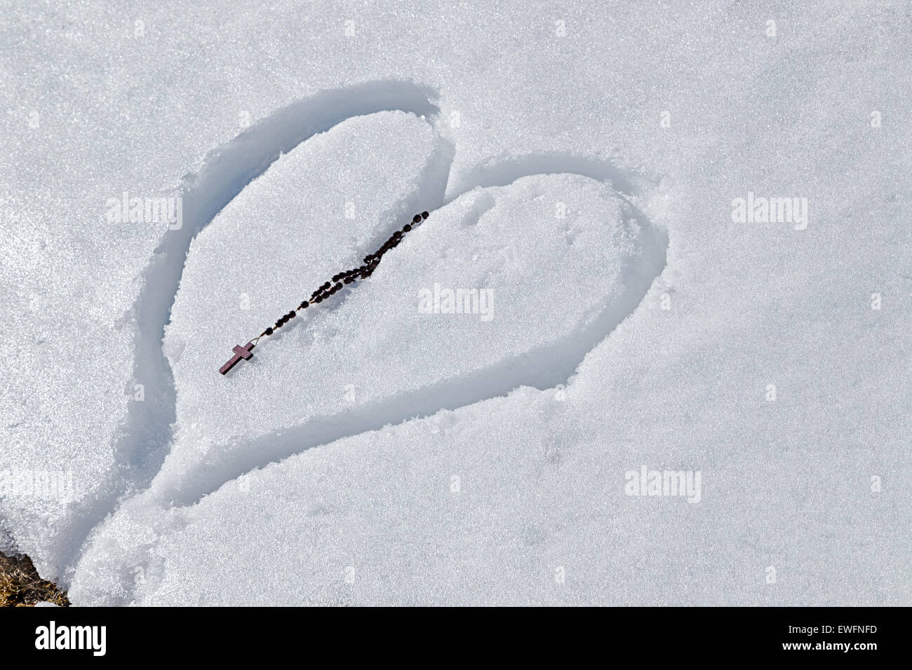 Rosario in legno Talloni a sinistra su un cuore disegnato a mano nella neve fresca Foto Stock
