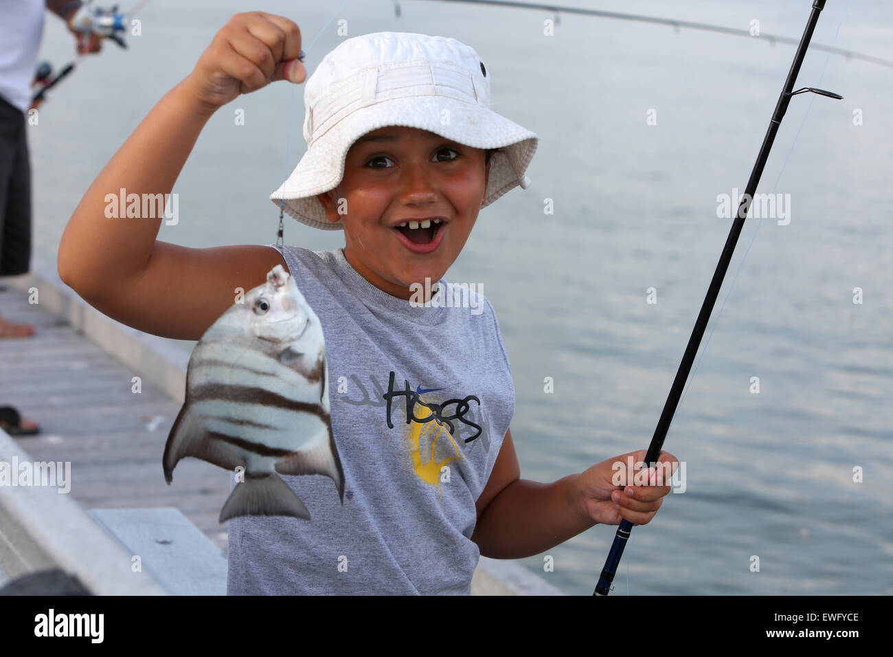 Passare una griglia Beach, Stati Uniti d'America, ragazzo mostra con orgoglio il suo pescato il pesce Foto Stock