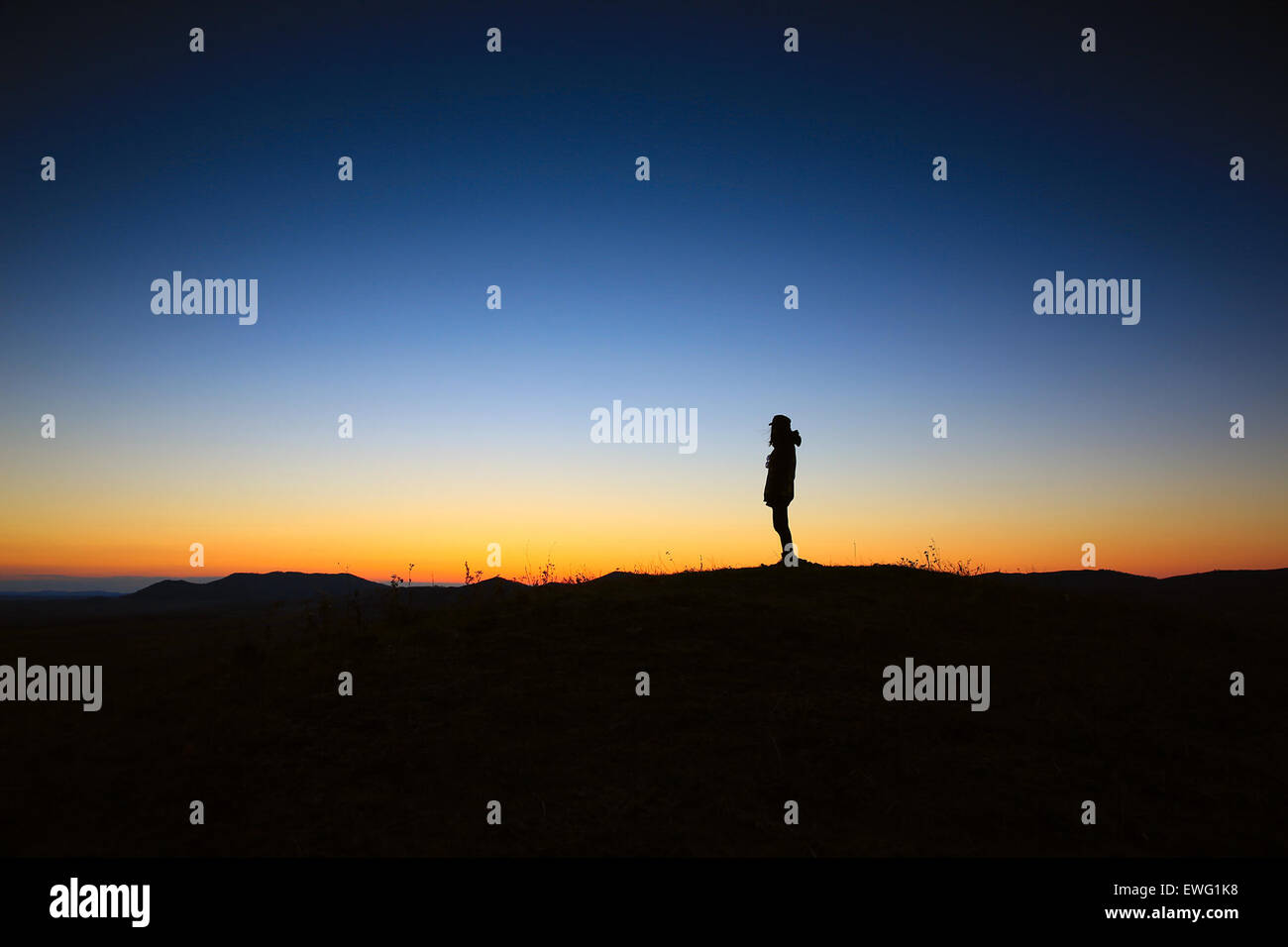 Una persona in piedi con th il tramonto dietro di loro silohette Foto Stock