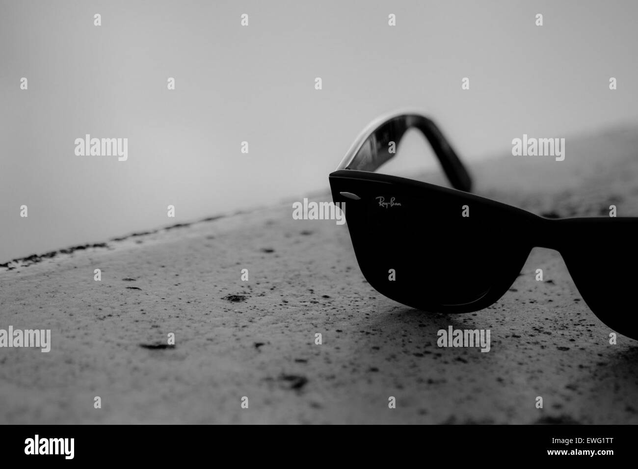 Immagine minimalista in bianco e nero degli occhiali da sole Ray-Ban esposti su un piano portapaziente. L'attenzione è rivolta al design iconico e alla qualità di questi occhiali da sole, che catturano il loro stile elegante e senza tempo. Foto Stock
