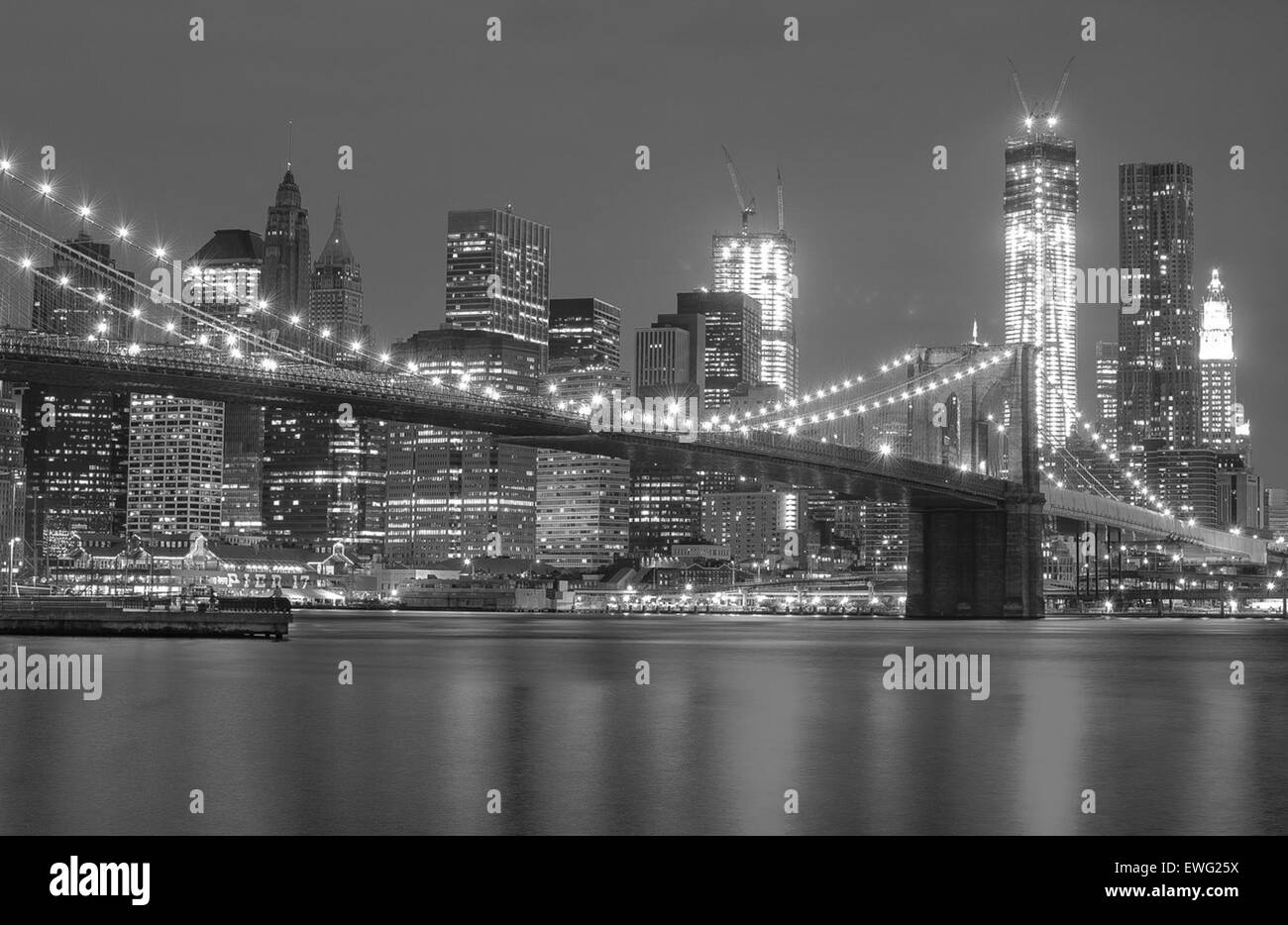 Un paesaggio notturno del Ponte di Brooklyn, con lo skyline illuminato di New York sullo sfondo. I cavi di sospensione e l'architettura del ponte sono chiaramente visibili contro il cielo scuro. Foto Stock