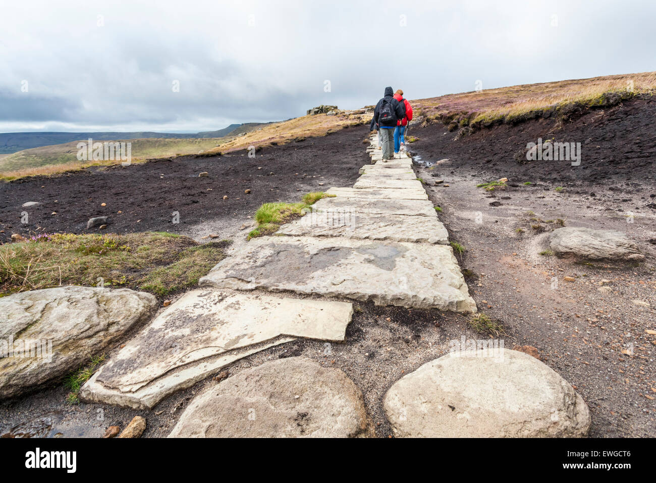 Mori restauro. Gli escursionisti escursionismo su una pietra bandiera sentiero pavimentato su Kinder Scout brughiera, Derbyshire, Parco Nazionale di Peak District, England, Regno Unito Foto Stock
