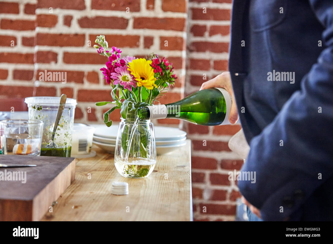 L'uomo analizzato il vino in un bicchiere di fiori in background di fronte rosso parete di rottura Foto Stock