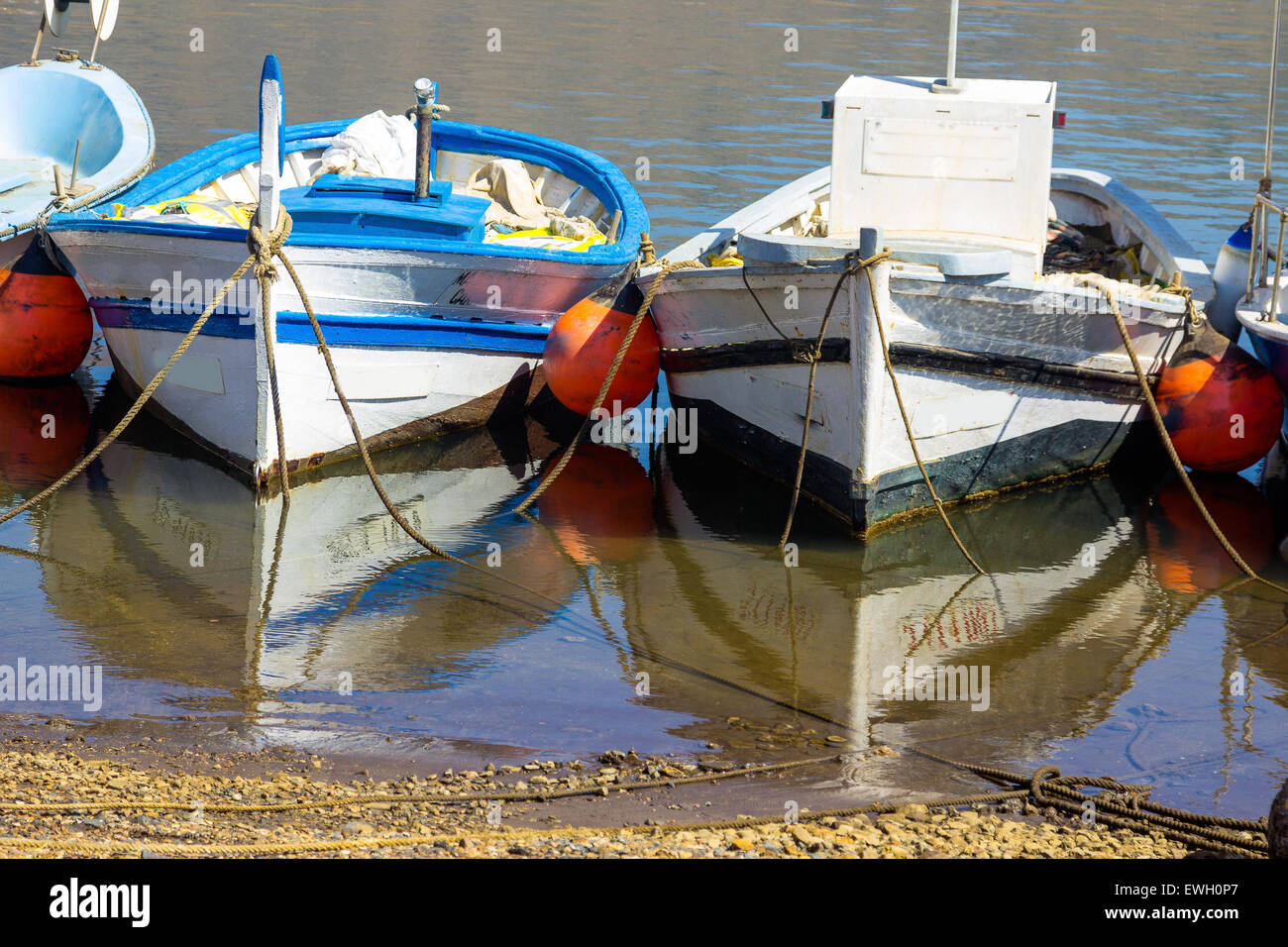 Vecchie barche da pesca legata alla spiaggia con mare calmo e riflessioni Foto Stock