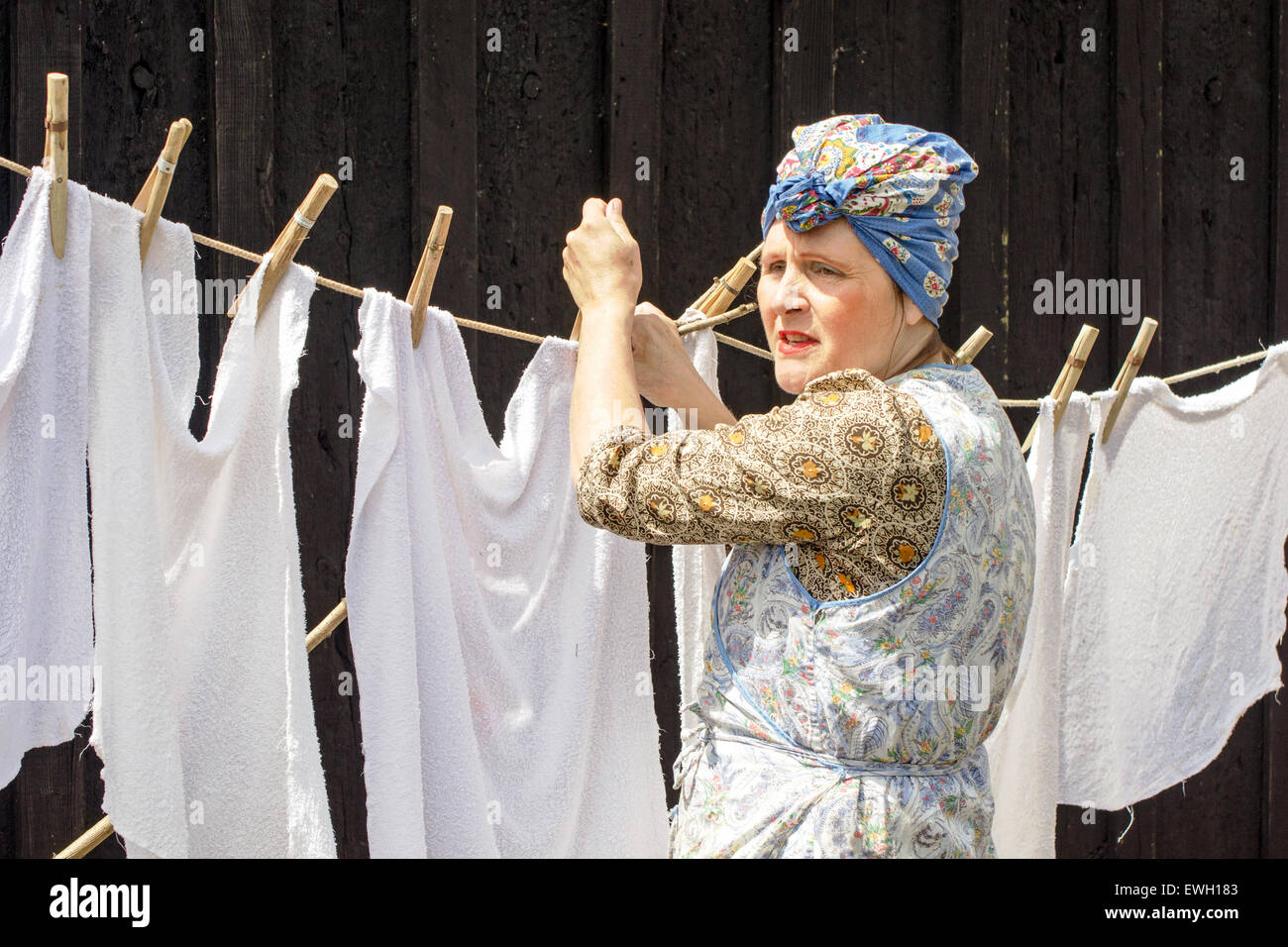 Una Donna vestita in stile anni quaranta (WW2) casalinga appeso fuori lavaggio su una linea di abbigliamento. Foto Stock