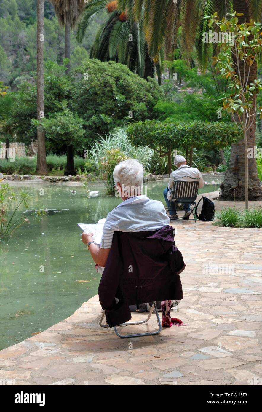 Disegno o pittura di artista senior mentre si siede in un botanico giardino Foto Stock