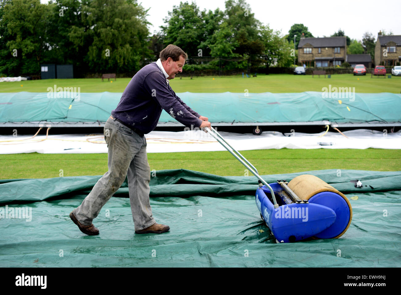 Un groundsman assorbendo acqua di pioggia sul campo da cricket utilizzando un archetto a secco. Immagine: Scott Bairstow/Alamy Foto Stock