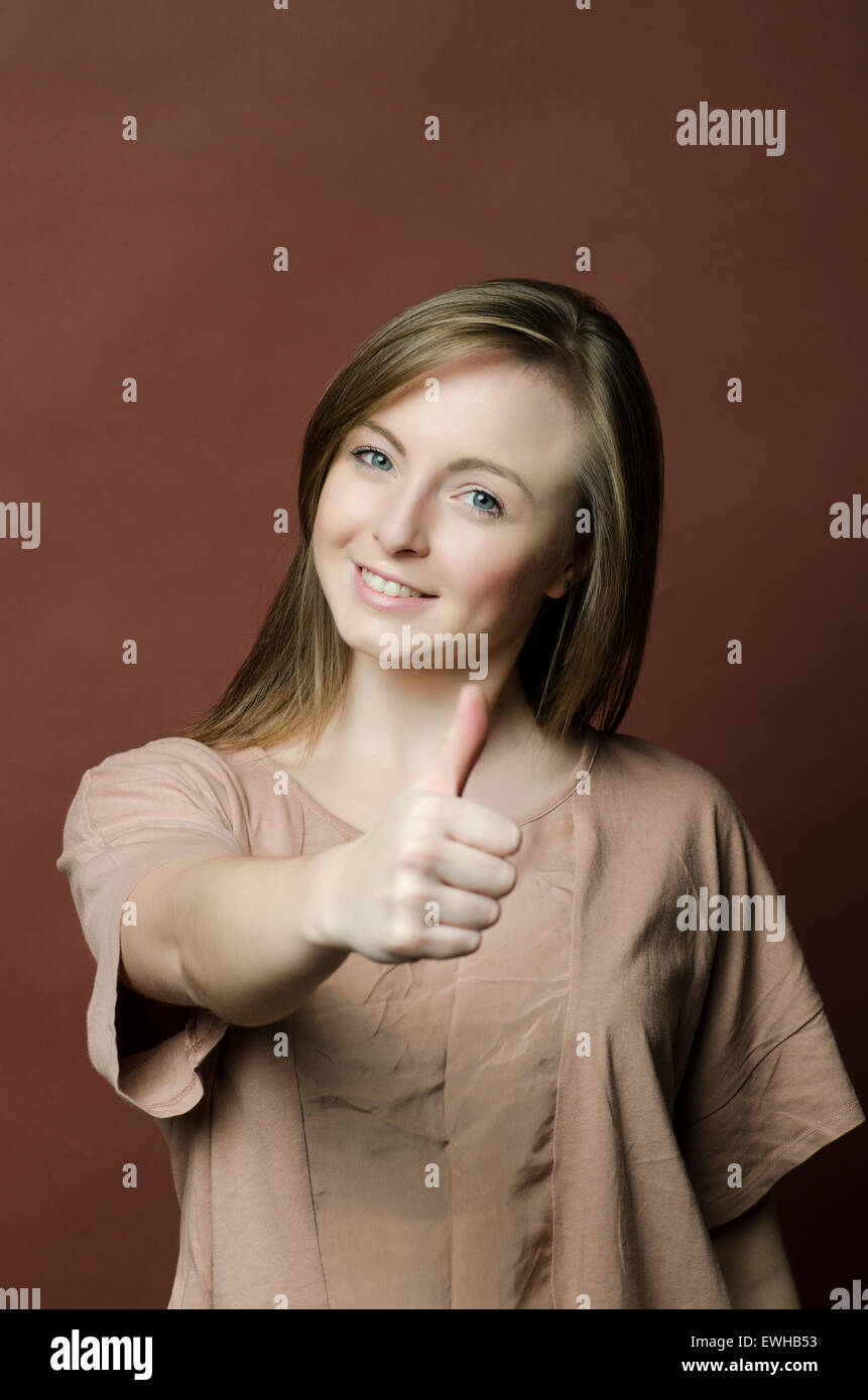 Felice giovane donna che mostra un pollice in alto gesto Foto Stock