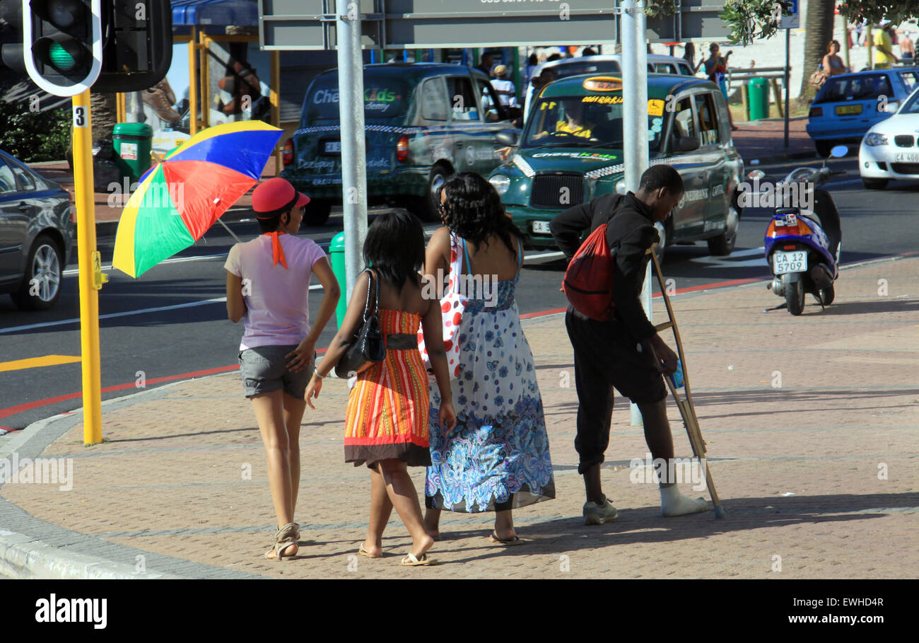 Cape Town, Sud Africa - 17 dicembre 2010: un gruppo di ragazze a piedi passato giovane ragazzo a mendicare per le strade. Foto Stock