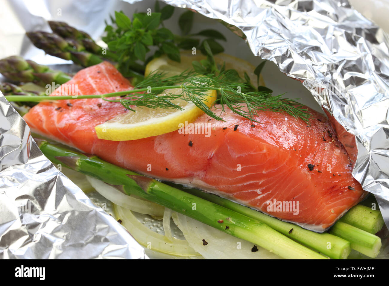 Salmone fresco con asparagi in carta stagnola, pronti per la cottura Foto Stock