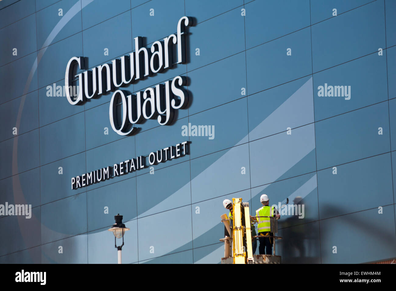 Operai in cherry picker lavorando sulla facciata di Gunwharf Quays Retail Premium Outlet a Portsmouth in giugno Foto Stock