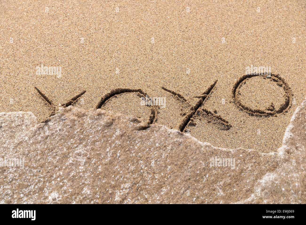 Baci e abbracci XOXO segno sulla spiaggia di sabbia Foto Stock