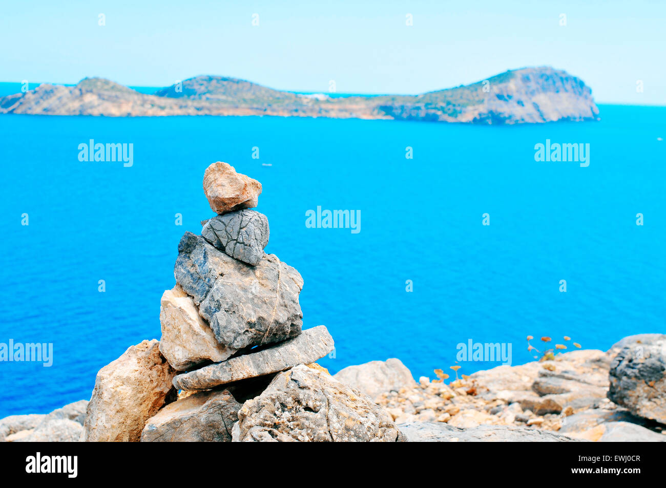 Primo piano di una pila di pietre equilibrato in Isola di Ibiza in Spagna, con il mar Mediterraneo e l'isola di Tagomago in backg Foto Stock