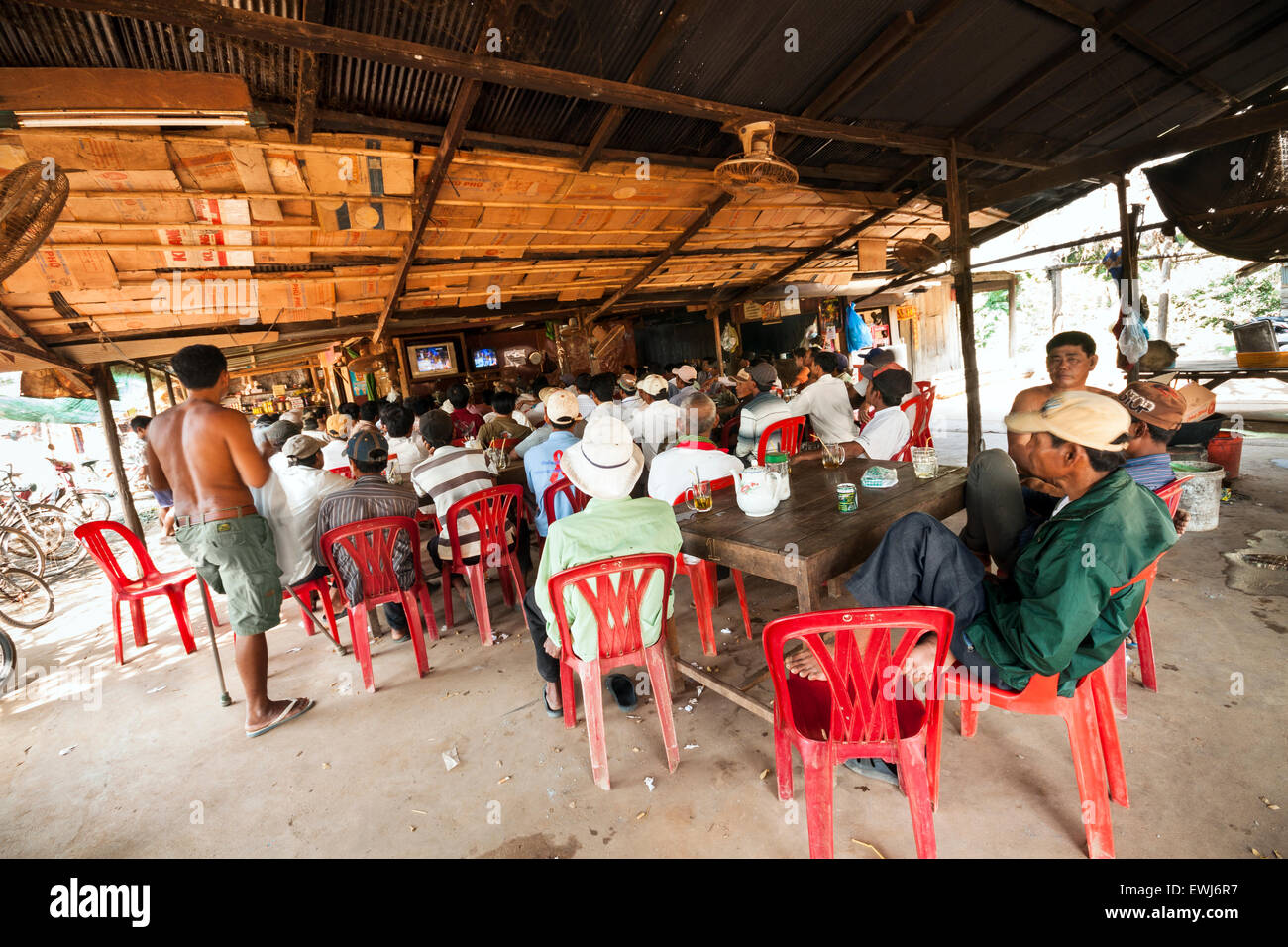 I cambogiani guarda e scommesse sul match di boxe in un villaggio rurale shop. Foto Stock