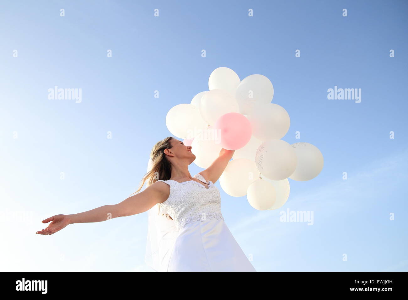 Una sposa felice con il bianco ballons nel cielo blu Foto Stock