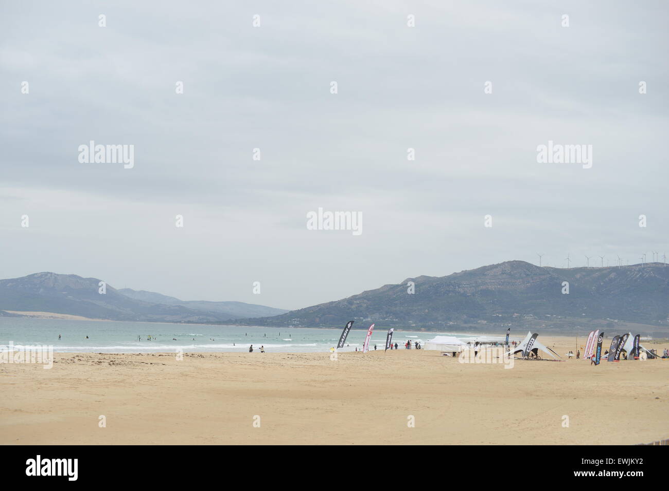 Surfisti sulla spiaggia in una giornata di vento di Tarifa, Spagna, nel novembre 23th, 2009. Impianti di energia eolica sulla cima della montagna. Foto Stock