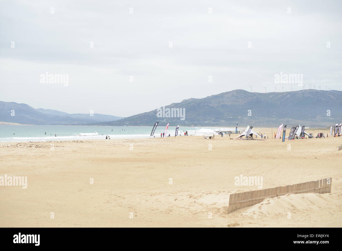 Surfisti sulla spiaggia in una giornata di vento di Tarifa, Spagna, nel novembre 23th, 2009. Impianti di energia eolica sulla cima della montagna. Foto Stock