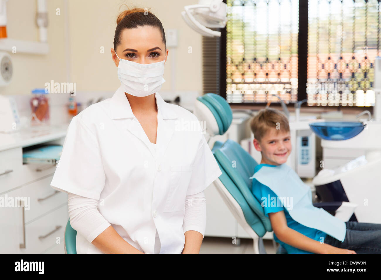 Ritratto di dentista femmina in ufficio con bambino malato in background Foto Stock