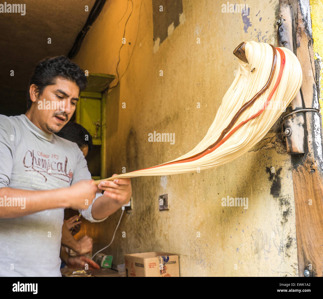 L'uomo facendo melcocha taffy su un piolo di legno in Banos, Ecuador. Foto Stock