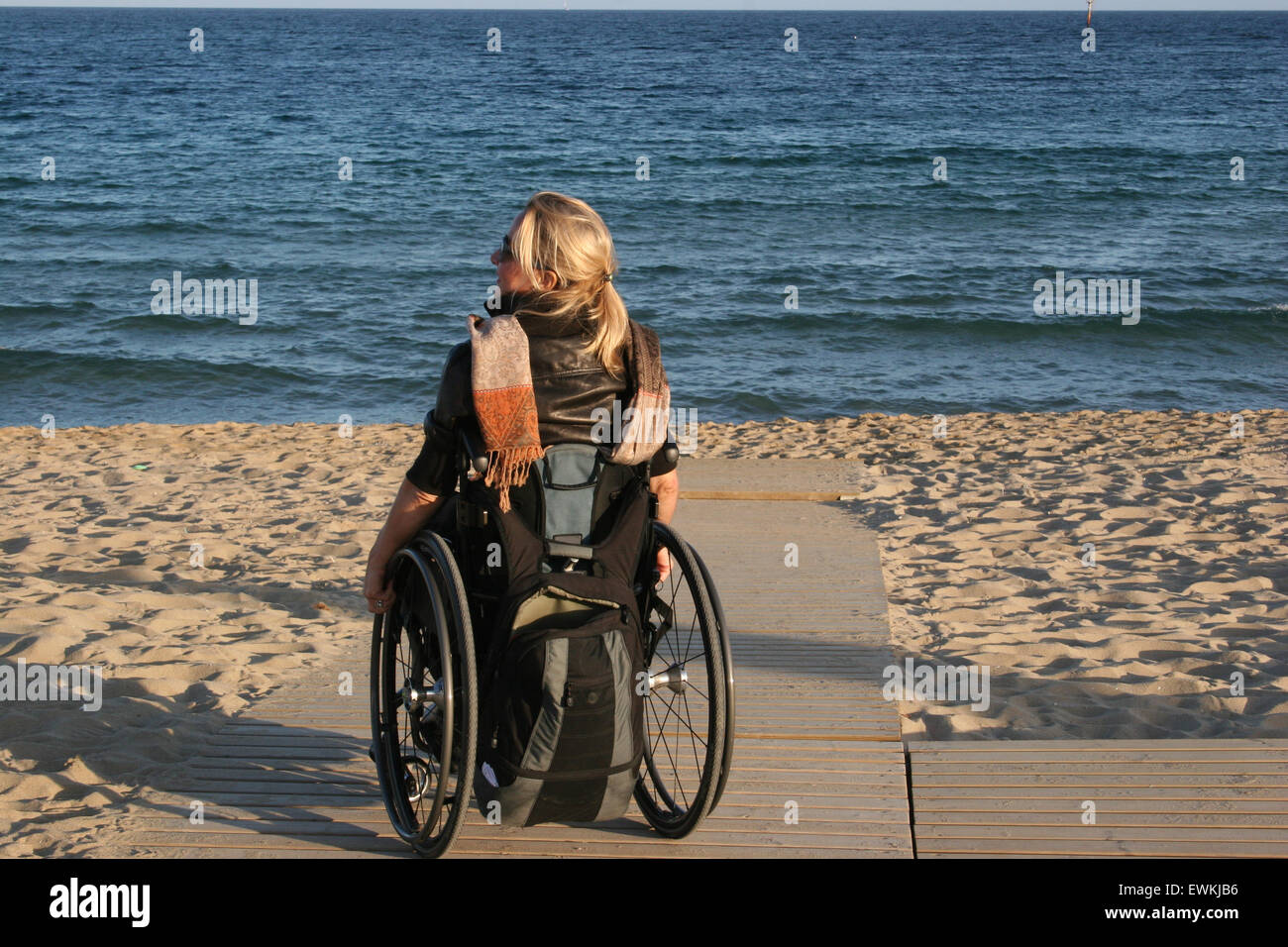 Una donna su una sedia a rotelle su una spiaggia rampa di accesso Foto Stock