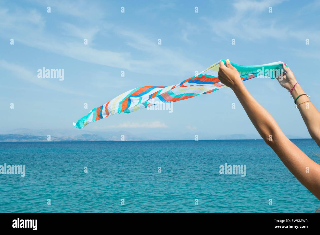 Ragazza in abito bianco sventola una sciarpa colorata sul mare Foto Stock