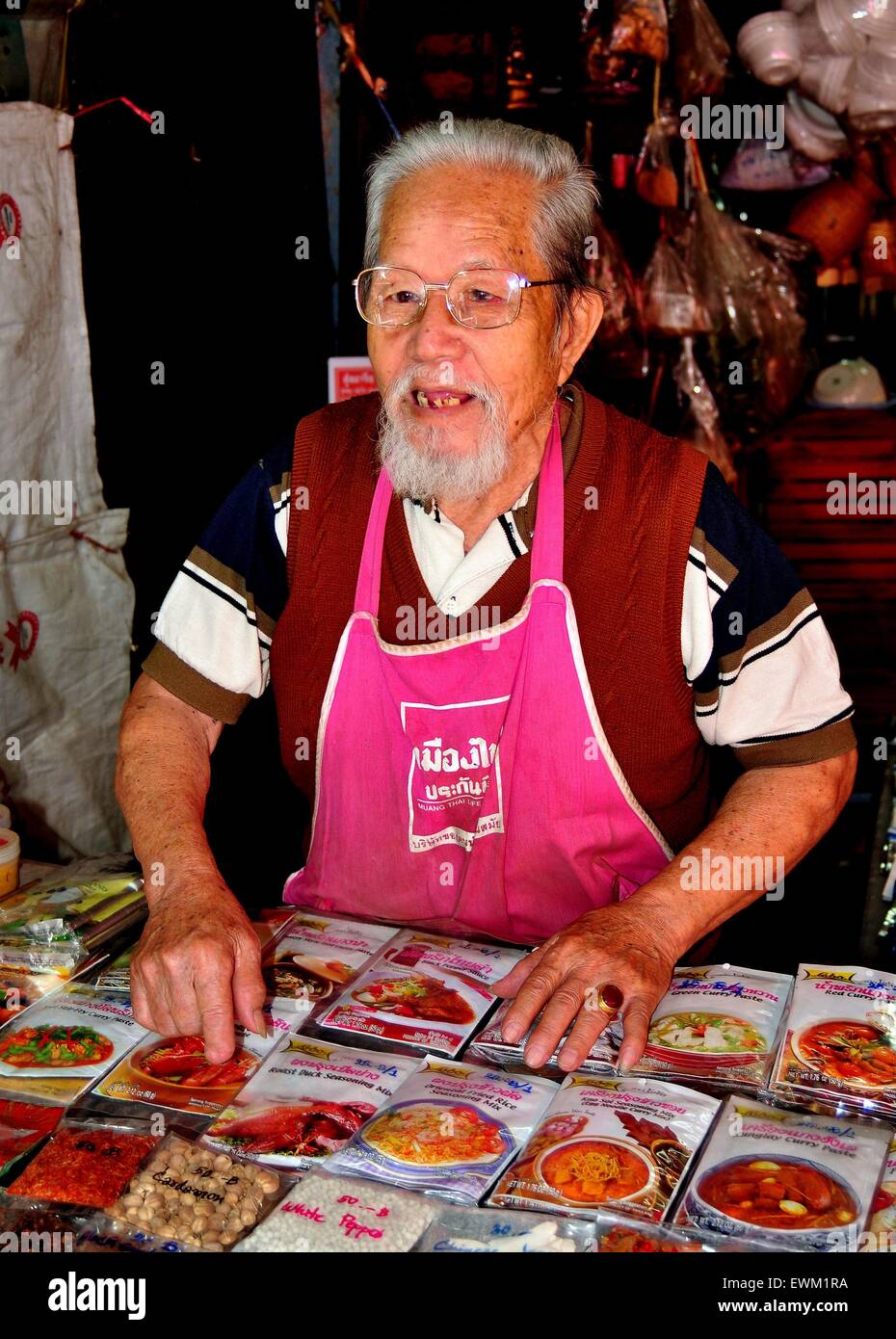 Chiang Mai, Thailandia: Anziani Chinese-Thai uomo vendita di salsa preparata si mescola nel suo stand al Somphet mercato alimentare Foto Stock