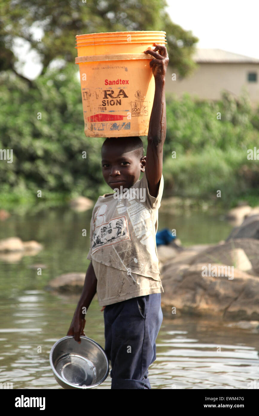 I giovani sono utilizzando in Africa per attingere acqua per la famiglia. Un 9 anno vecchio ragazzo bello il prelievo di acqua per la sua famiglia presso il fiume. Foto Stock