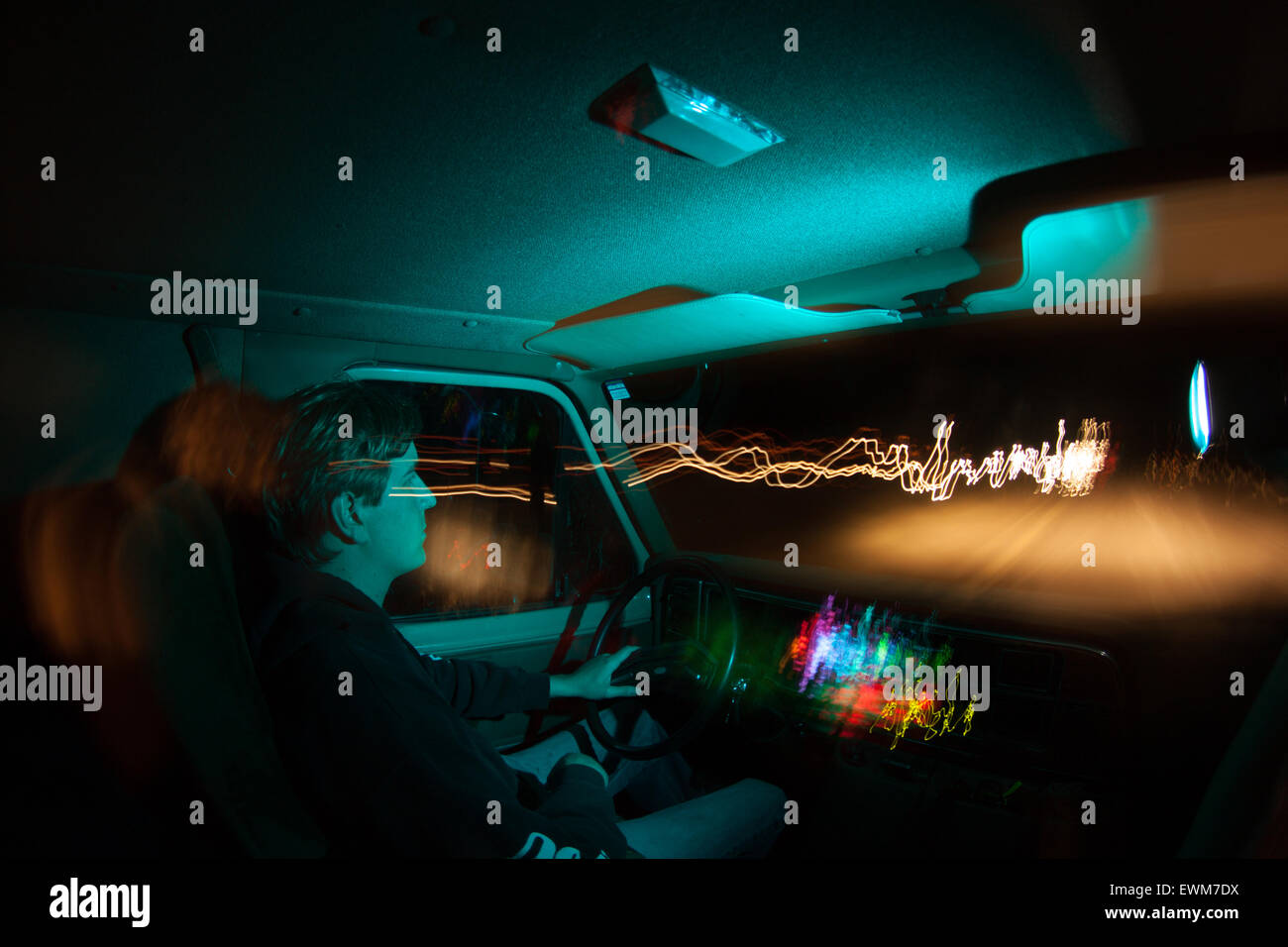 Un uomo trascina lungo il percorso 66 di notte, con striature di luce dai fari degli autoveicoli in transito. Foto Stock