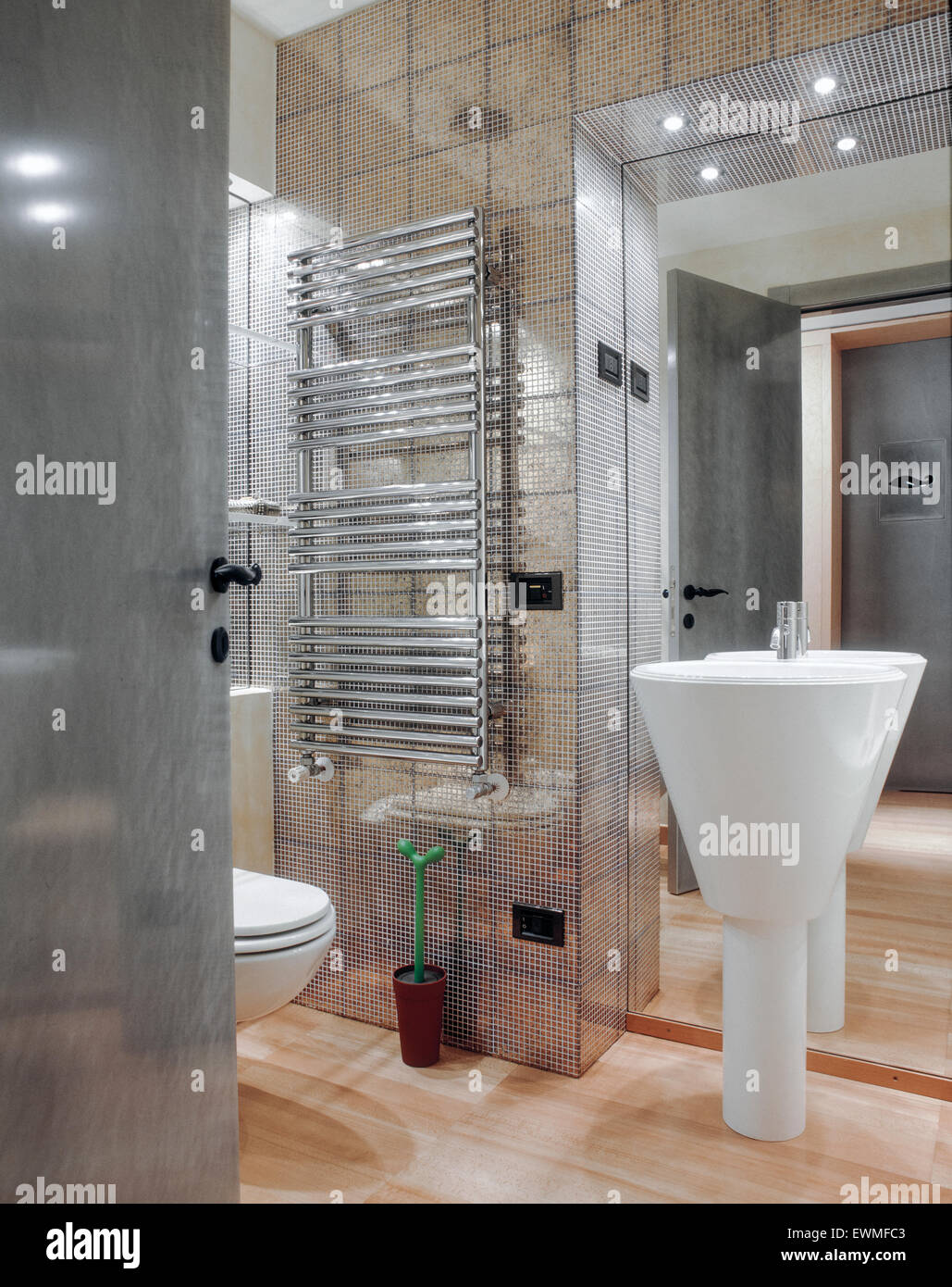 In primo piano del lavandino in una moderna stanza da bagno con piastrelle a mosaico e pavimento in legno Foto Stock