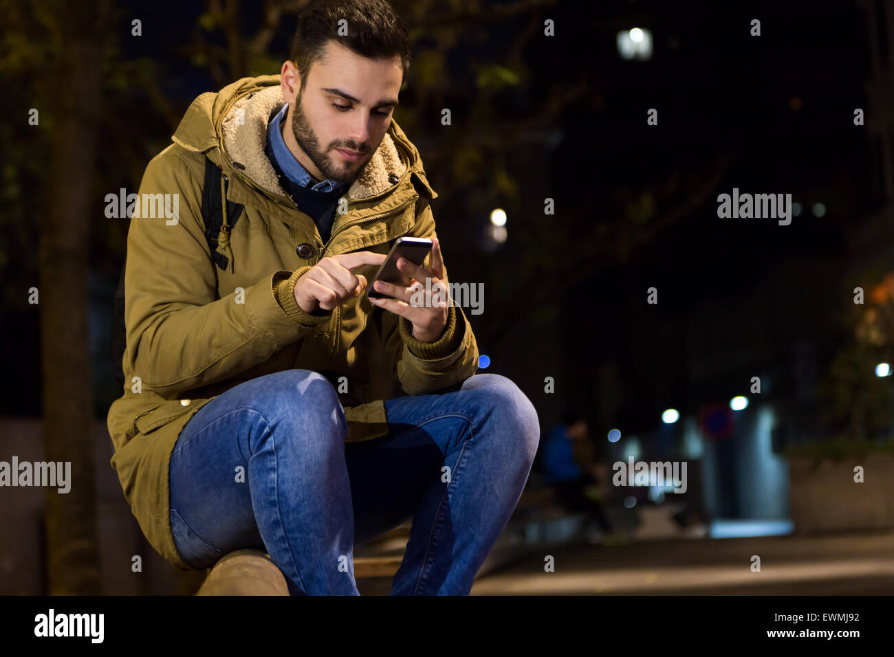 Outdoor Ritratto di giovane uomo con il suo telefono cellulare di notte. Foto Stock