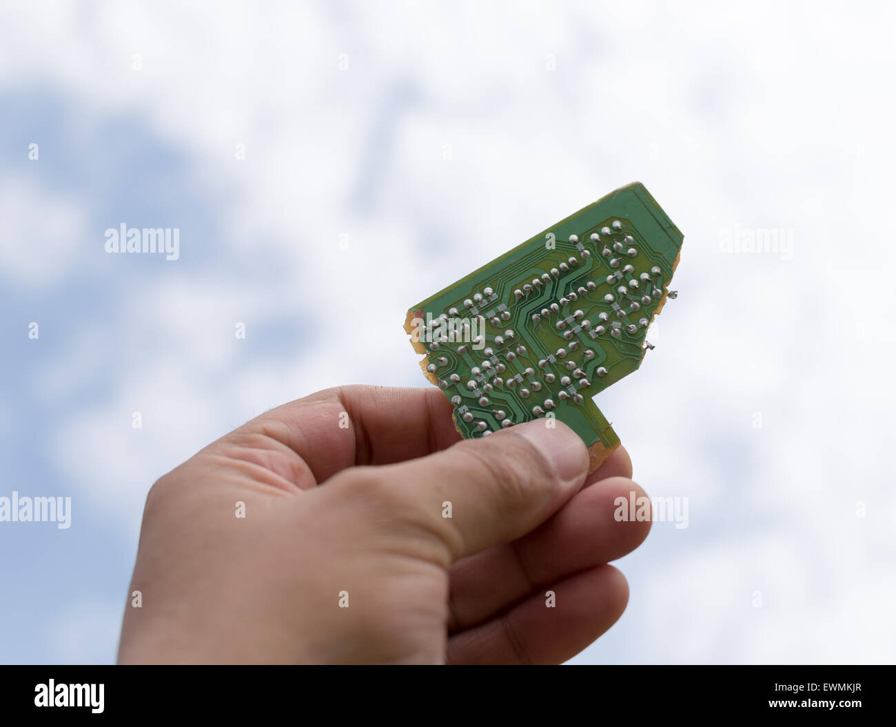 Maschio bianco mano che tiene un pezzo di un verde della scheda di circuito stampato fino al cielo Foto Stock