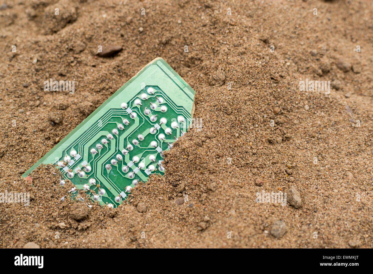 Rotture di verde della scheda PCB sepolto nella sabbia marrone Foto Stock