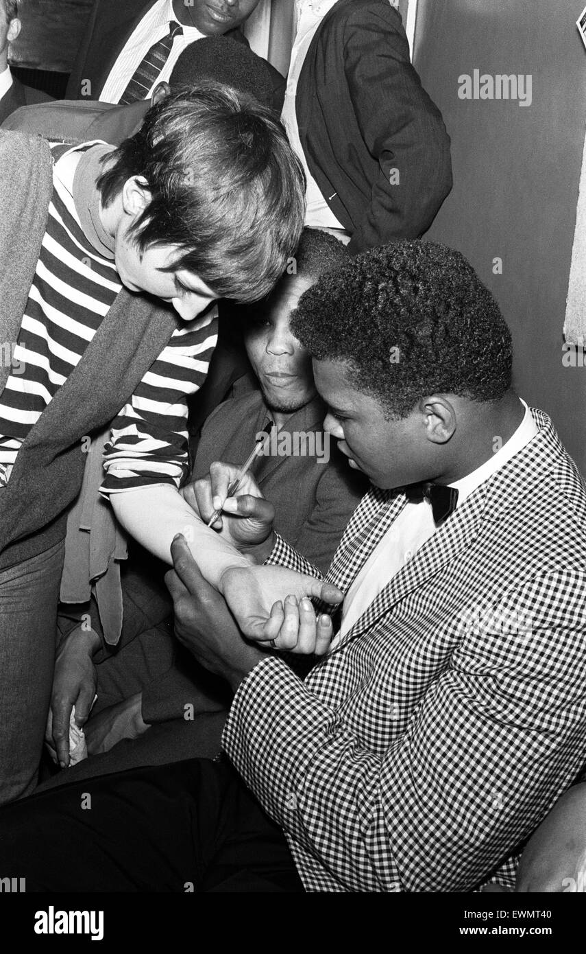 Cassio argilla (aka Muhammad Ali) segni il suo autografo su un fan dell'avambraccio in Londra in anticipo la sua prima lotta con Henry Cooper. 26 Maggio 1963 Foto Stock